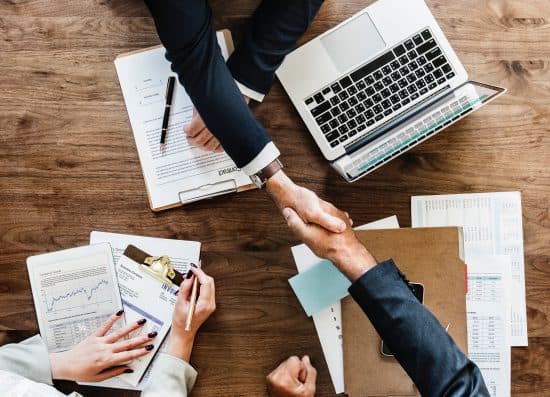 Two business people shaking hands across a wooden table