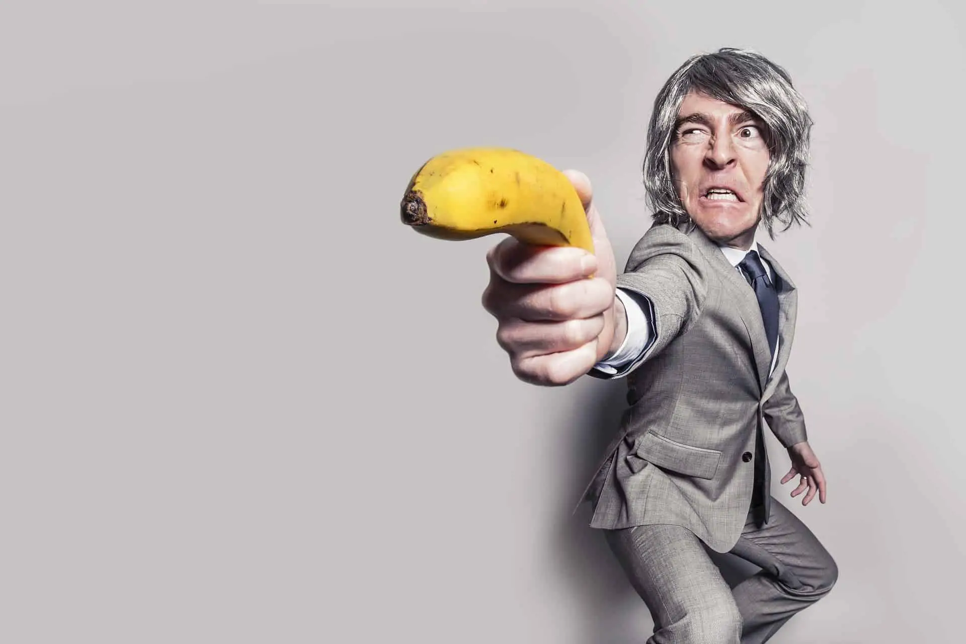 Man in a suit holding a banana like a gun