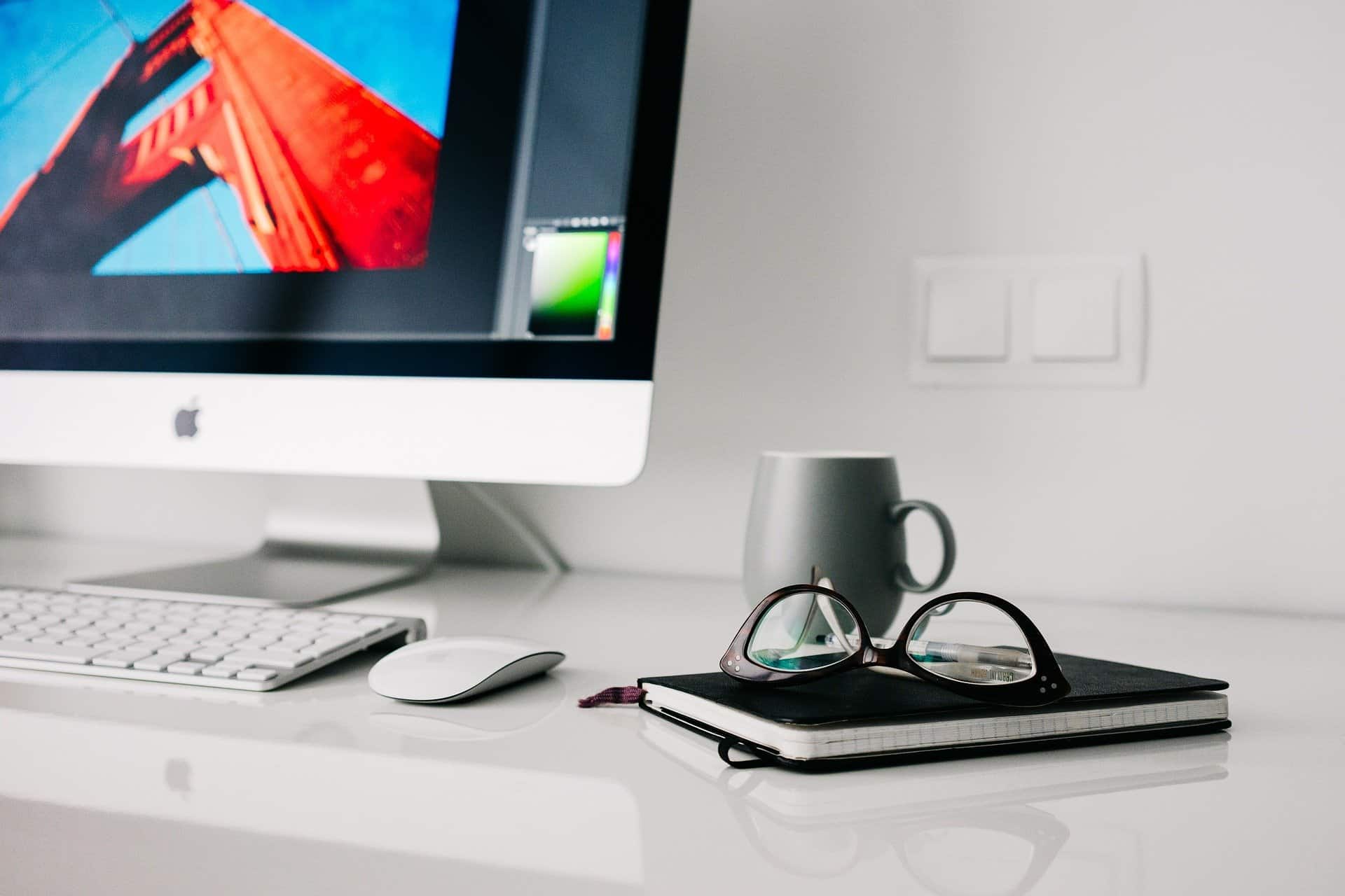 Glasses sitting on top of a journal next to a Mac computer