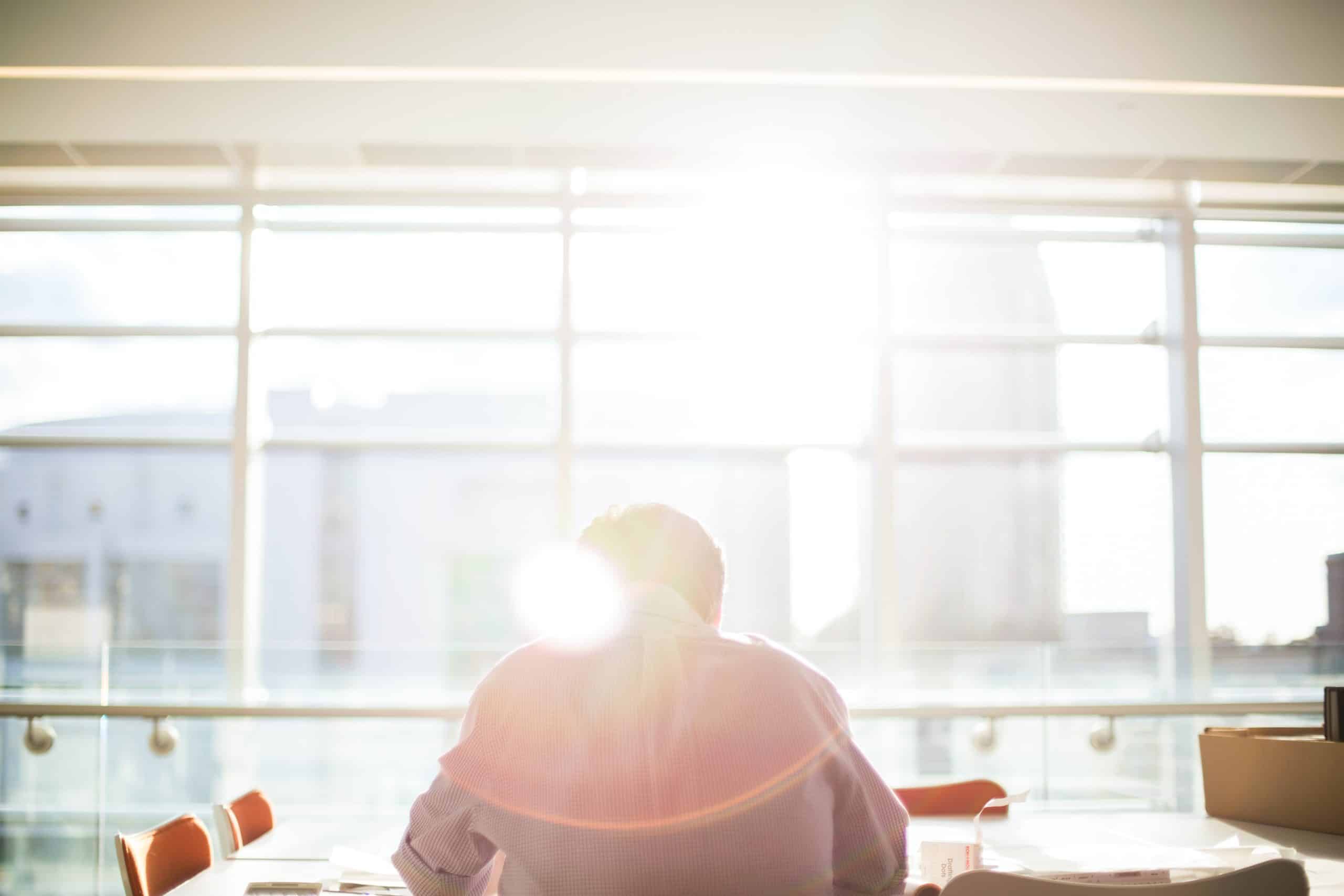 Man sitting at a window with the sun shining in