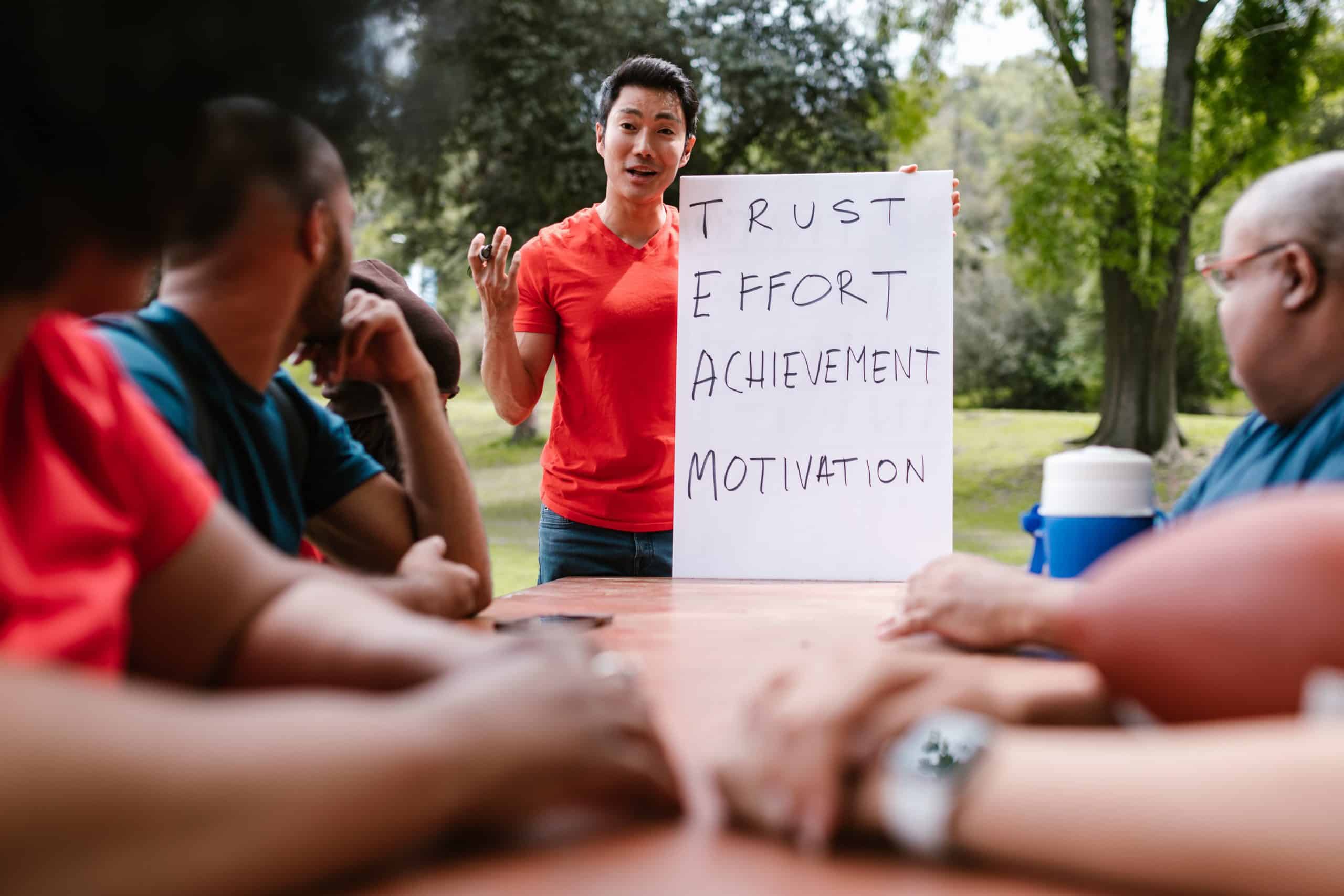 Man in a red shirt with a sign that shows the acronym for TEAM