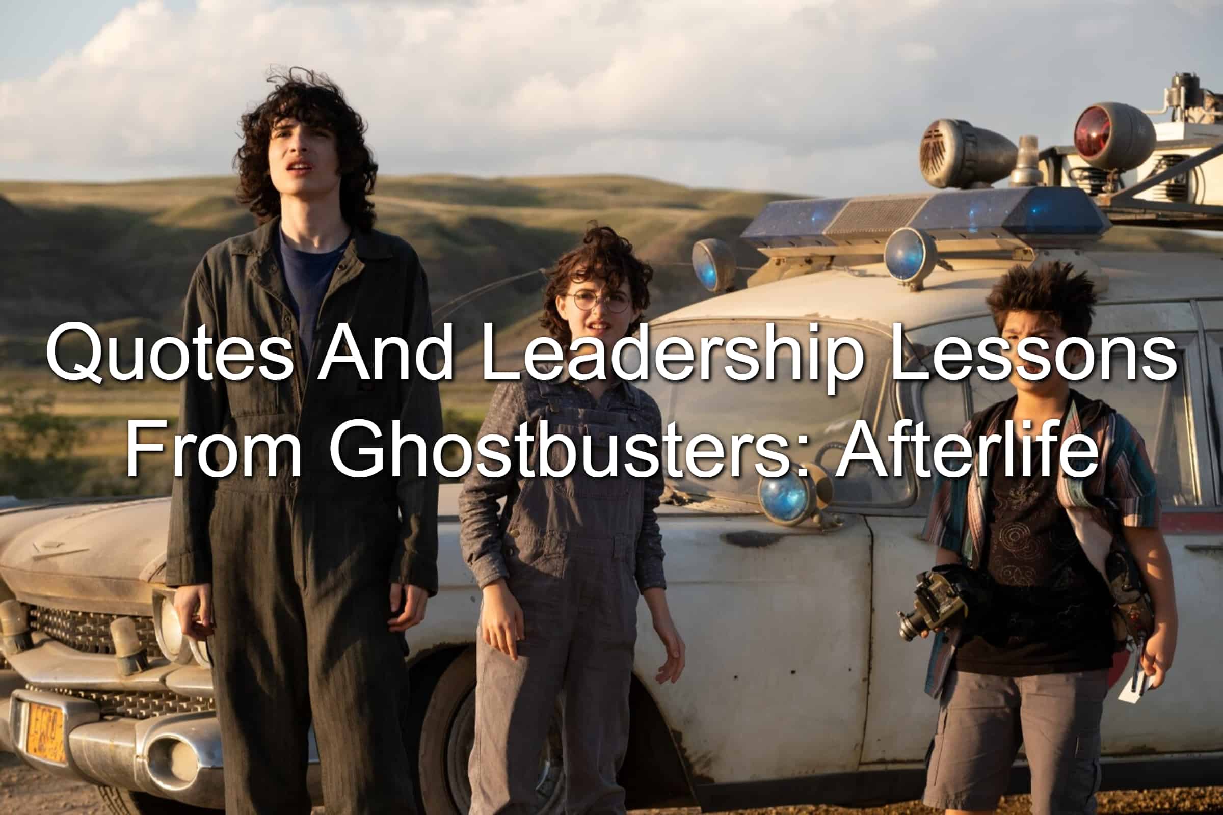 Kids from Ghostbusters: Afterlife standing in front of the Ecto-1 vehicle