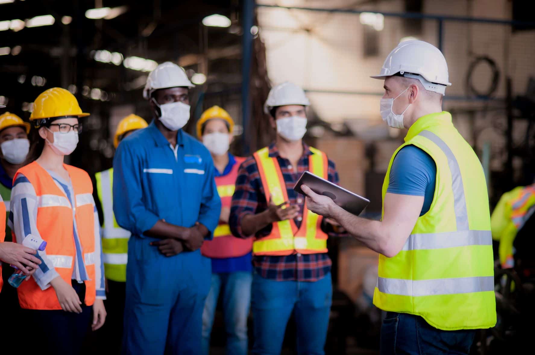 People with face masks and safety helmets in a meeting