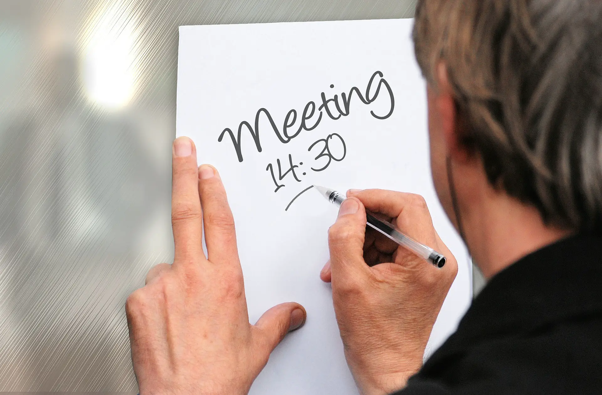 Man writing a note about a meeting