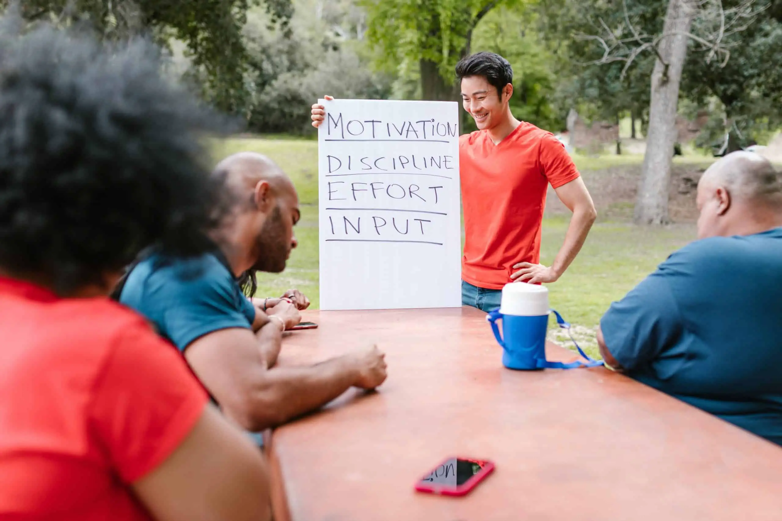 Man holding up a sign at a picnic table