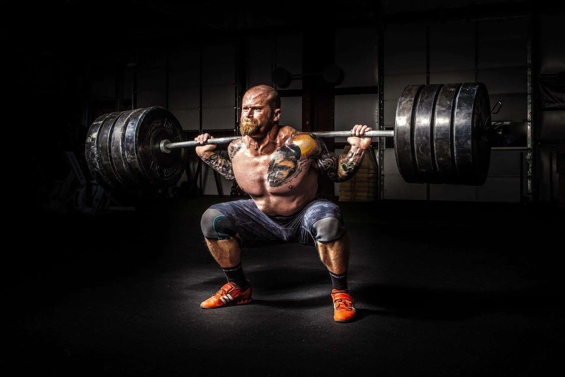 Man with tattoos doing a power squat
