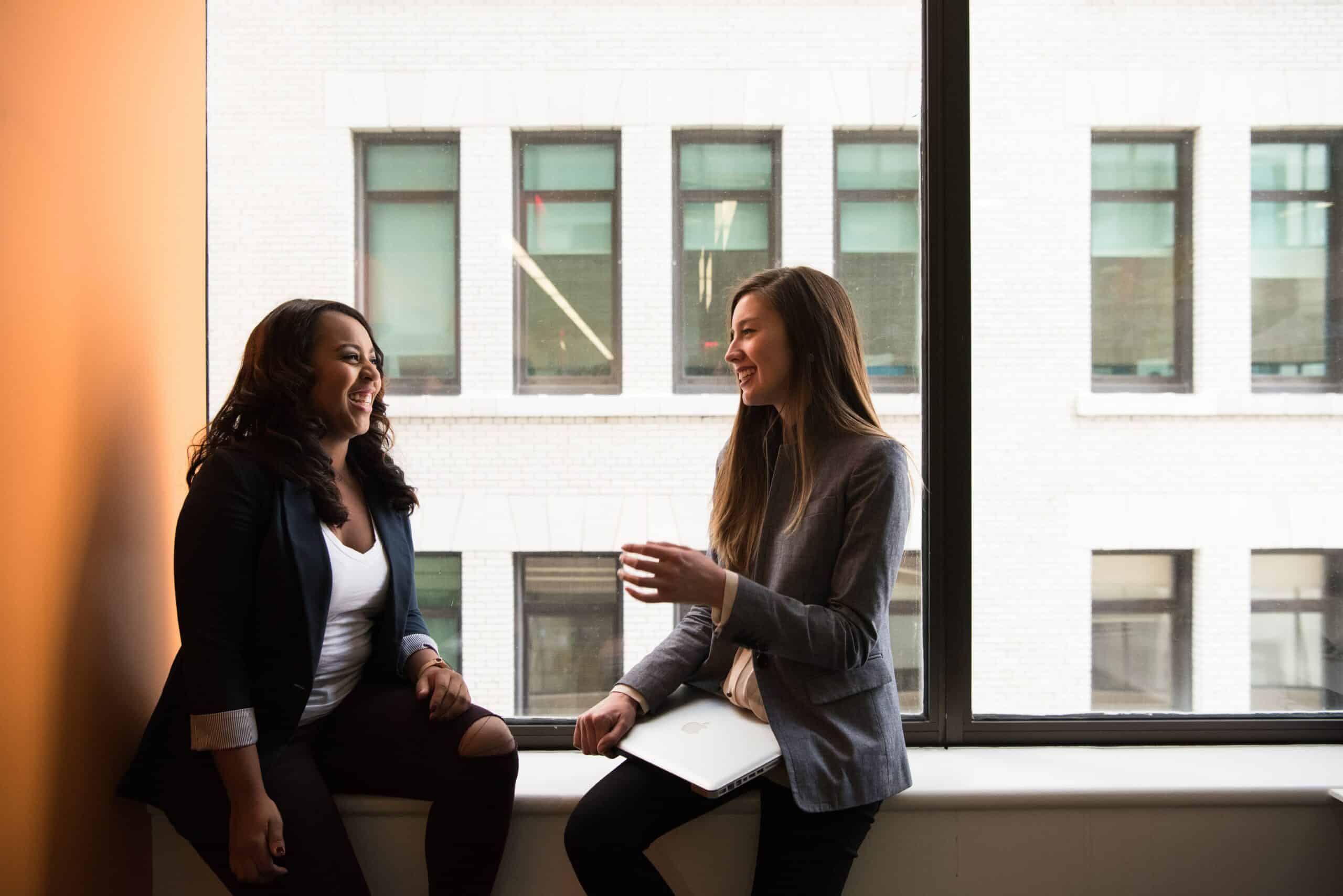 Two women having a conversation by a window