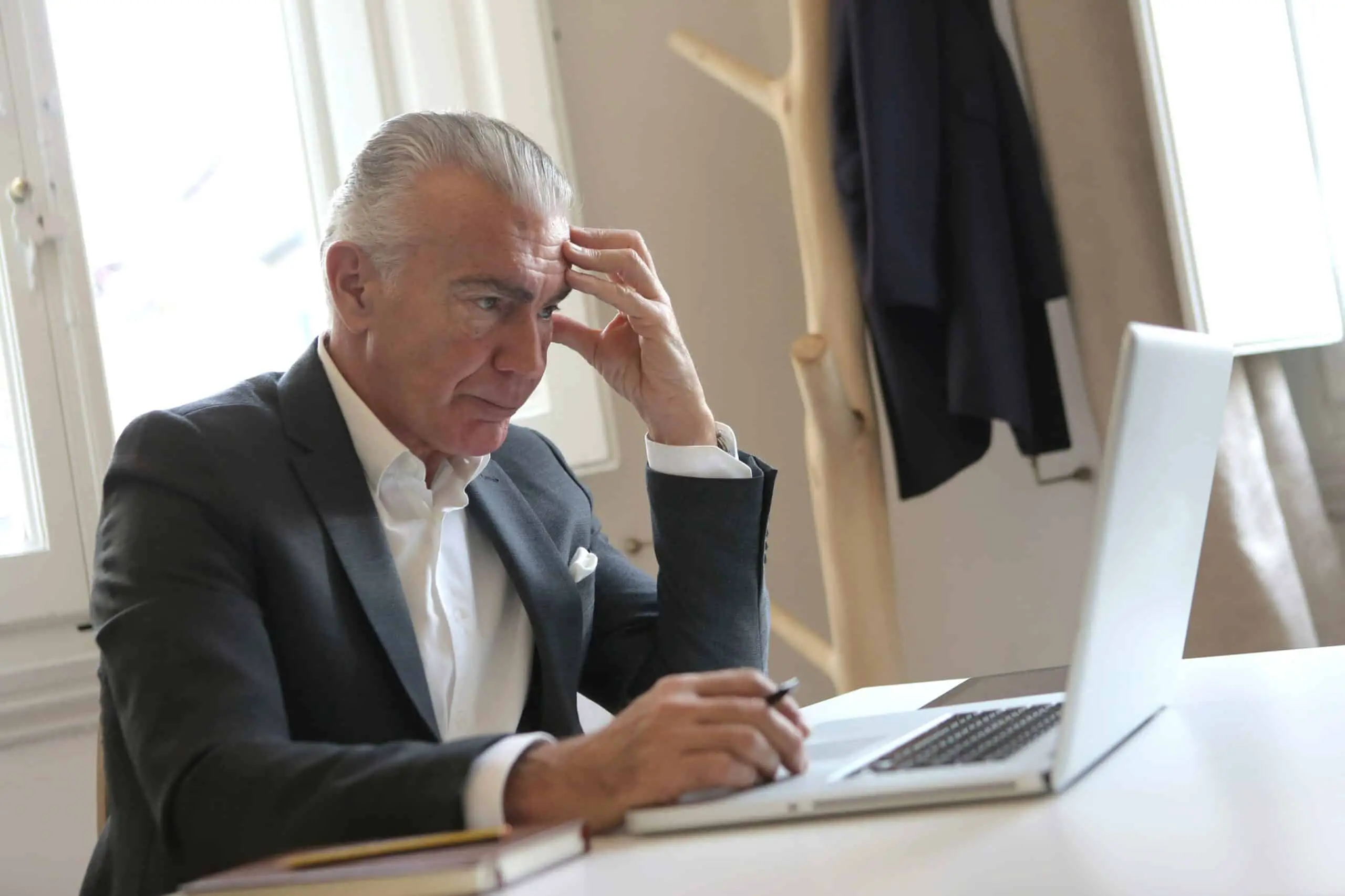 Man in a black suit looking at a laptop