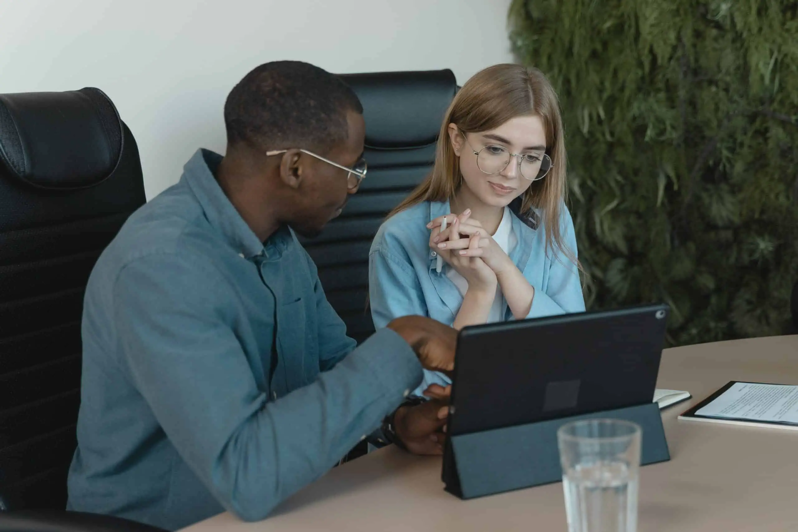 Man teaching a woman sitting in front of a Microsoft Surface