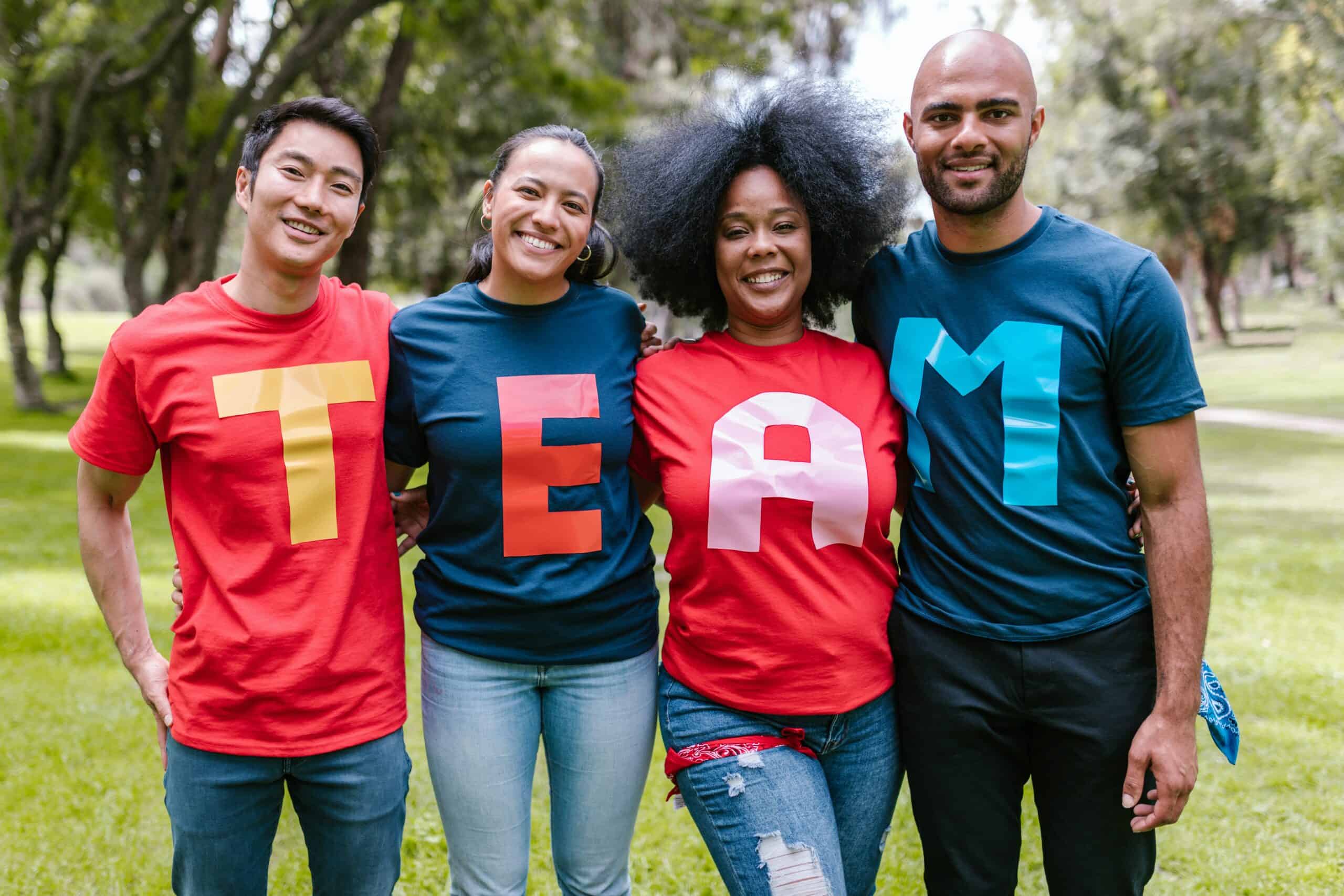 People wearing multiple colored shirts with letters. Together, it spells team.