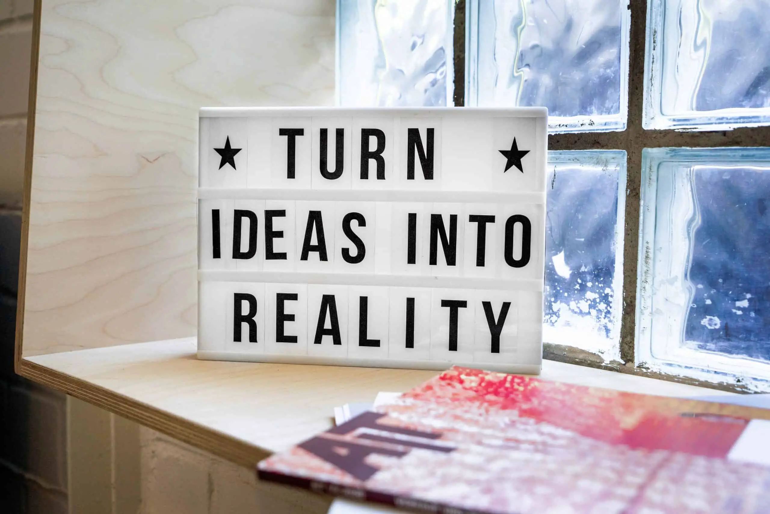 White sign on table saying "Turn Ideas Into Reality"